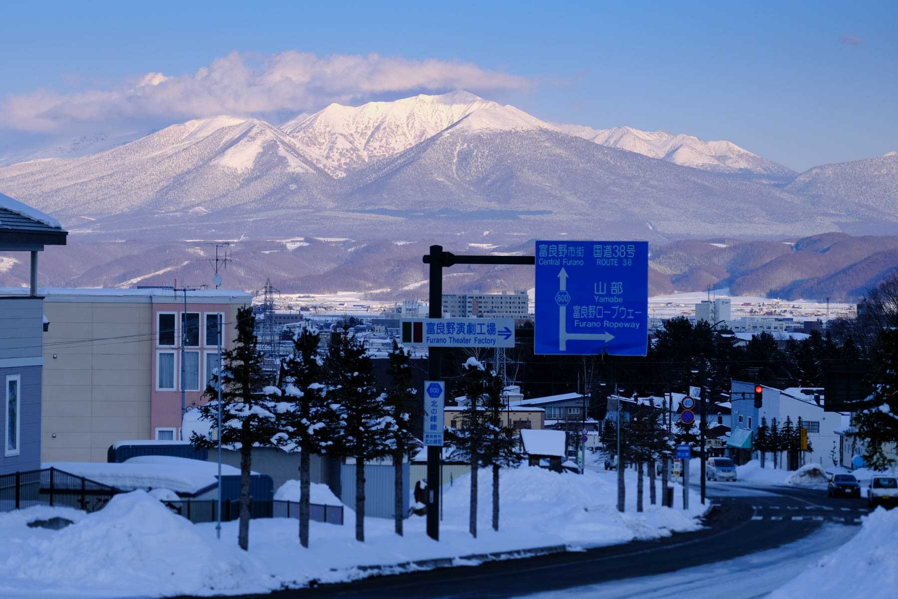 View from the car window showcasing stunning Furano landscapes, including snow-capped mountains and scenic valleys, during a journey through Japan.